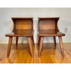 two wooden chairs sitting next to each other on top of a hard wood floored floor