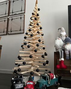 a small wooden christmas tree sitting next to a toy truck on top of a table