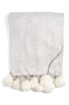 a gray blanket with white pom poms