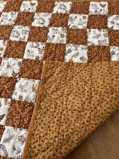 a brown and white quilt on top of a wooden floor