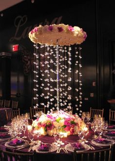 a table topped with lots of white and pink flowers next to tall glass vases