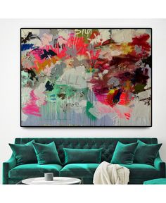 an abstract painting on the wall above a green couch