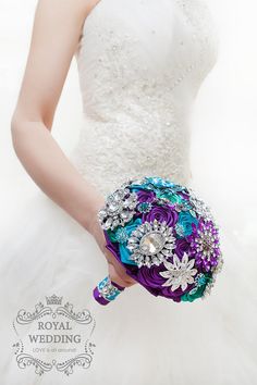 a woman in a wedding dress holding a purple and green bridal bouquet with brooches