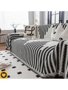 a black and white couch sitting on top of a floor next to a rug covered in pillows