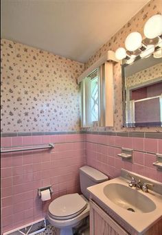 a bathroom with pink and white tiles on the walls, toilet, sink and mirror