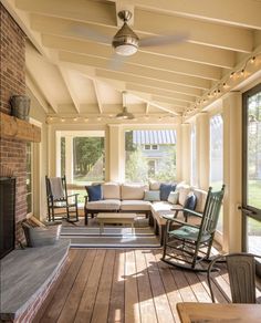 a covered porch with rocking chairs and couches next to a fire place in front of a fireplace