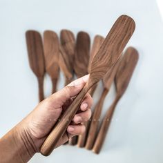 a hand holding wooden utensils in front of white background