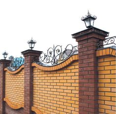 a brick wall with an iron fence and lampposts