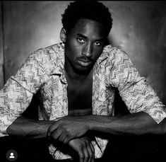 a black and white photo of a man with his hands on his knees looking at the camera