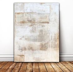 an abstract painting on a wall in a room with wooden flooring and white walls