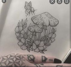 a hand holding a piece of paper with tattoos on it and a drawing of mushrooms in the background