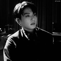 black and white photo of a young man sitting in front of a piano with his head turned to the side