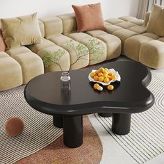 a black coffee table with fruit on it in the middle of a living room area