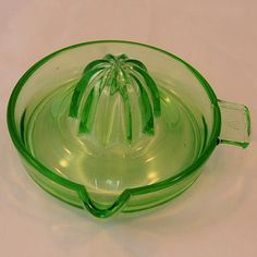 a green glass bowl sitting on top of a white table