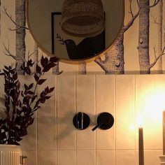 there is a mirror above the sink in this bathroom with trees on the wall behind it