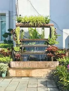 an outdoor fountain surrounded by plants and flowers