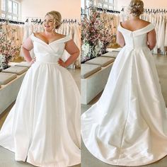 a woman standing in front of a mirror wearing a white wedding dress with an off the shoulder neckline