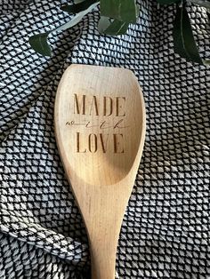 a wooden spoon with the words made in love written on it next to some leaves