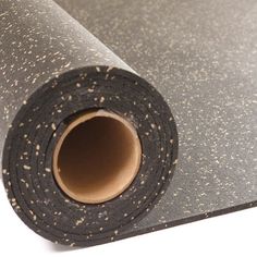 a roll of black and white speckled carpeting on top of a white surface