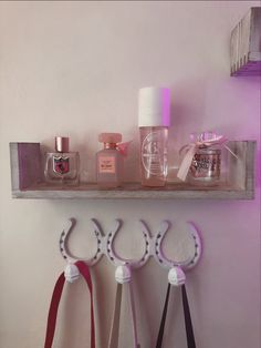 three pairs of scissors are hanging on a shelf with perfume bottles and other items in the background