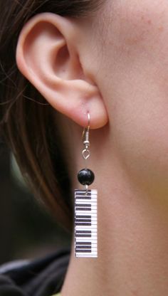 a close up of a person wearing some kind of earring with piano keys on it