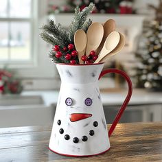 a snowman mug filled with wooden spoons on top of a table next to a christmas tree