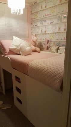 a small child's bedroom with pink bedding and wallpaper