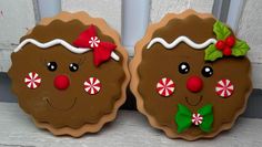 two gingerbread cookies decorated to look like they are wearing christmas hats and candy canes