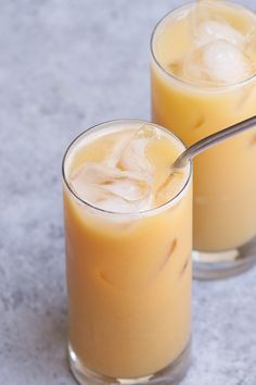 two glasses filled with drinks sitting next to each other on top of a gray table