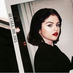 an old photo of a woman with dark hair and red lipstick, taken in front of a mirror