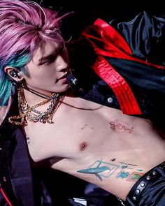 a man with pink hair and piercings on his chest