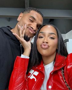 a man standing next to a woman in a red leather jacket