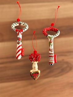 three christmas ornaments hanging from strings on a wooden surface