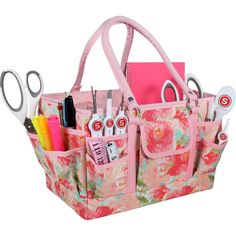 a pink flowered bag with scissors and pens in it is sitting on a white surface