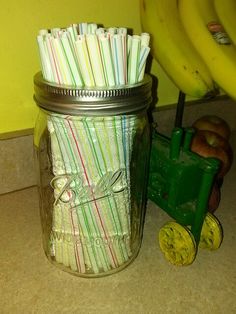 a mason jar filled with candy canes next to some bananas and a green toy tractor