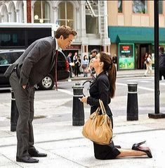 a man kneeling down next to a woman on the ground in front of a fire hydrant