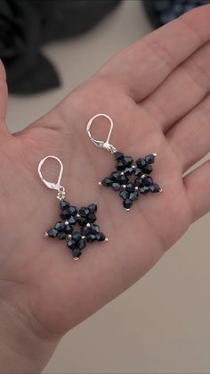 a person is holding some kind of black beaded earrings on their palm and it looks like they have been made out of beads