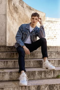 a man sitting on some steps with his hands in his hair and looking at the camera