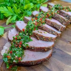 sliced meat with herbs and seasoning sitting on a cutting board