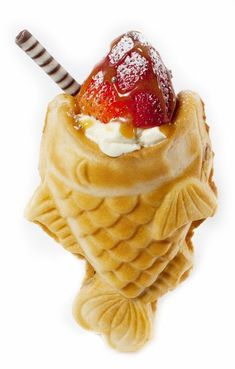 an ice cream sundae with strawberries and whipped cream in a waffle cone