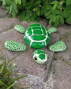 a green turtle statue sitting on top of a cement slab next to some grass and bushes