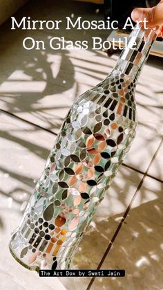 a hand holding a glass bottle made out of circles on the side of a tile floor