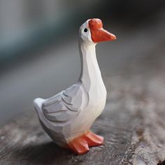 a white and orange duck sitting on top of a piece of wood