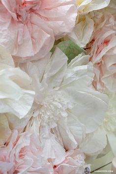 large pink and white flowers are in the middle of a bouquet, with green leaves