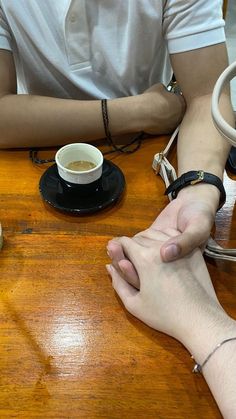 two people sitting at a table holding hands