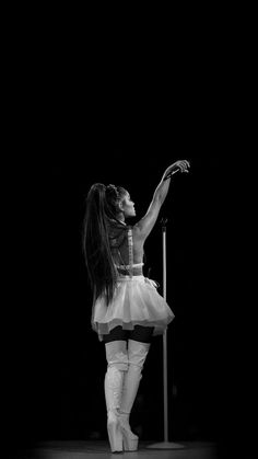 a woman in white tights and knee high boots standing on a stage with her arms outstretched