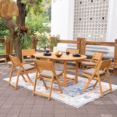 a wooden table and chairs sitting on top of a rug in front of a tree