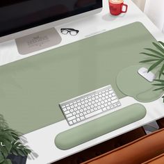 a computer desk with a keyboard, mouse and plant on it in front of a monitor