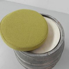 a round green cushion sitting on top of a metal container