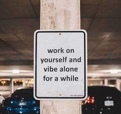 a sign that is on the side of a pole in a parking garage saying work on yourself and vibe alone for a while